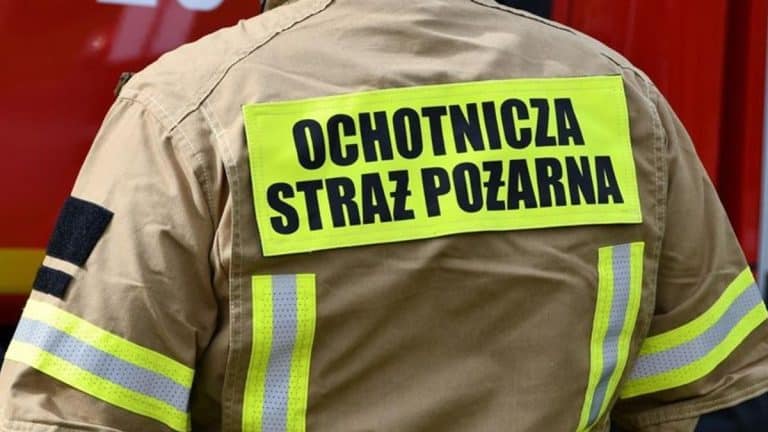 Ubranie strażaka z napisem 'Ochotnicza Straż Pożarna' na plecach, widziane od tyłu.