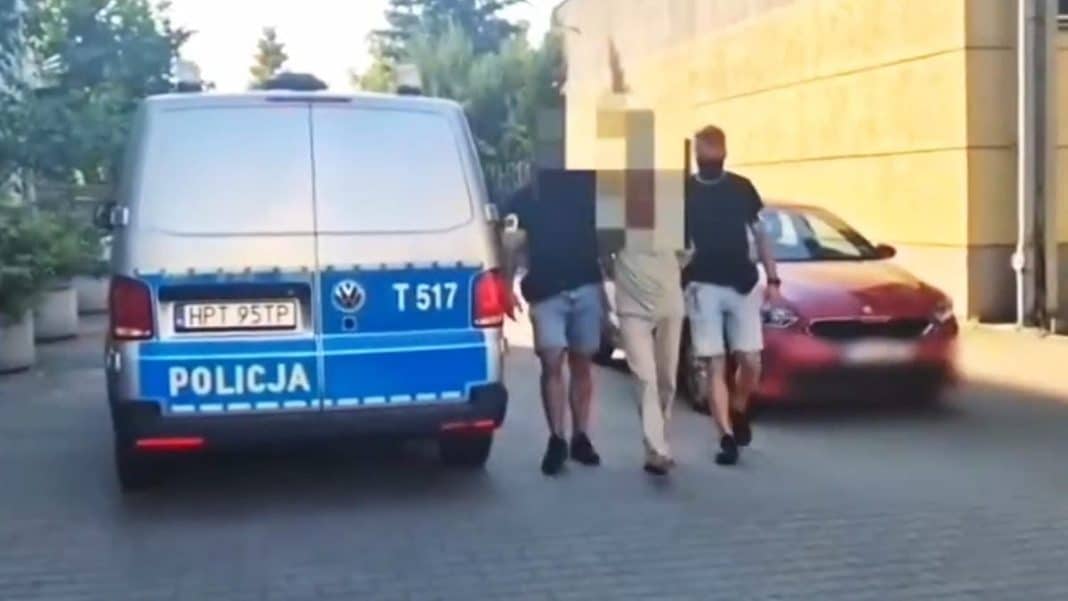 Policjant prowadzony przez funkcjonariuszy po zatrzymaniu podejrzanego w związku z tajemniczą paczką.