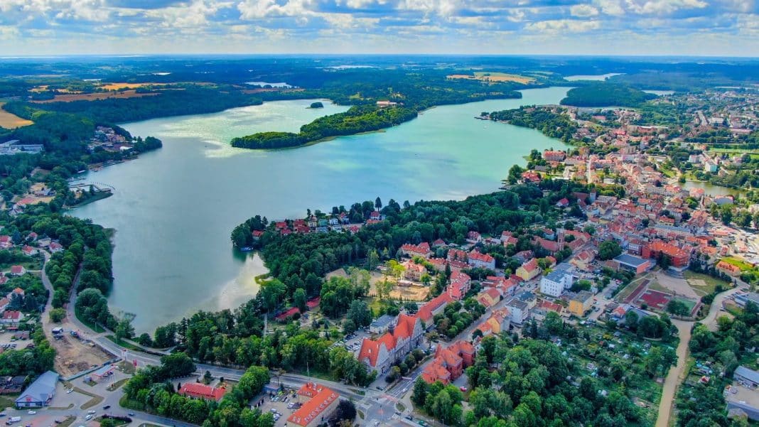 Widok na jezioro Czos i okoliczne tereny z lotu ptaka, zieleń i zabudowania w tle.
