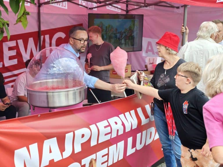 Osoba rozdająca watę cukrową na pikniku nad jeziorem Ukiel podczas wydarzenia Lewica w Olsztynie.
