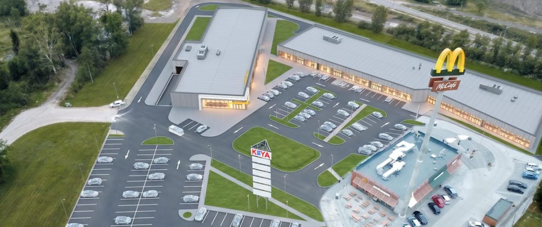 Nowoczesny park handlowy w Giżycku z supermarketem i parkingiem, w trakcie budowy.