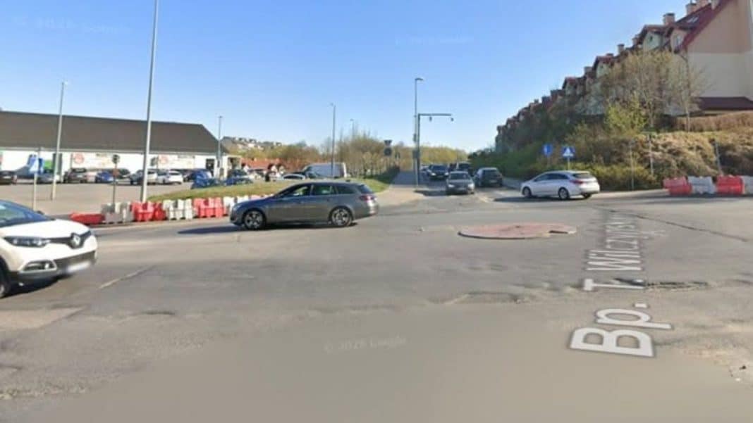 Widok na skrzyżowanie ulic Wilczyńskiego i Tuwima w Olsztynie z samochodami i wyłączonym pasem dla tramwajów.