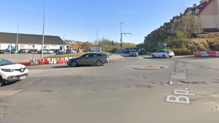 Widok na skrzyżowanie ulic Wilczyńskiego i Tuwima w Olsztynie z samochodami i wyłączonym pasem dla tramwajów.