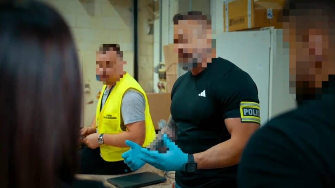 Funkcjonariusz policji trzyma paczkę z narkotykami podczas akcji służbowej.