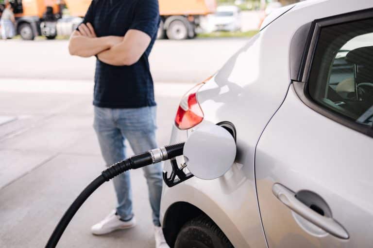 Mężczyzna stojący obok samochodu podczas tankowania LPG na stacji benzynowej.