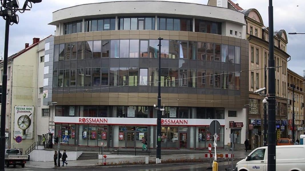 Widok na nowoczesny budynek z dużymi oknami i sklepem Rossmann na parterze, w centrum miasta.