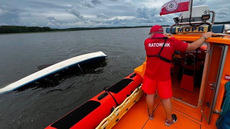 Ratownik na łodzi ratunkowej przy wywróconej jednostce na jeziorze Stręgiel.