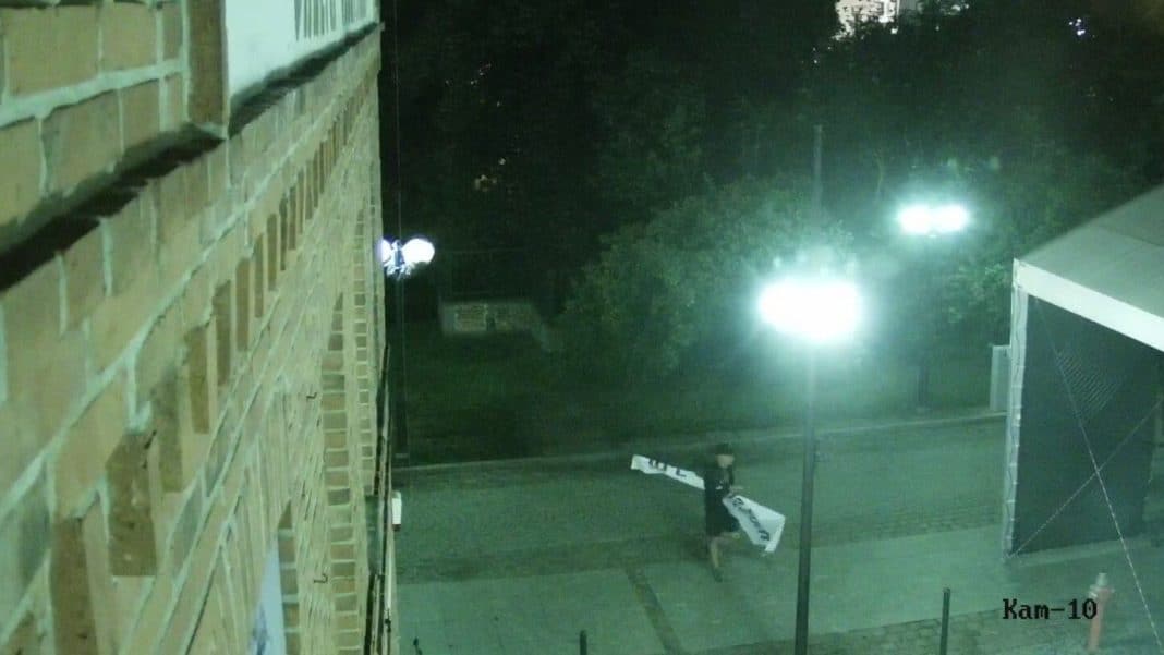 Mężczyzna sprzątający ulicę nocą w centrum Olsztyna, przy Wysokiej Bramie, na monitoringu miejskim.