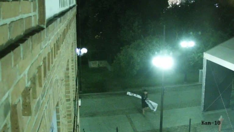 Mężczyzna sprzątający ulicę nocą w centrum Olsztyna, przy Wysokiej Bramie, na monitoringu miejskim.