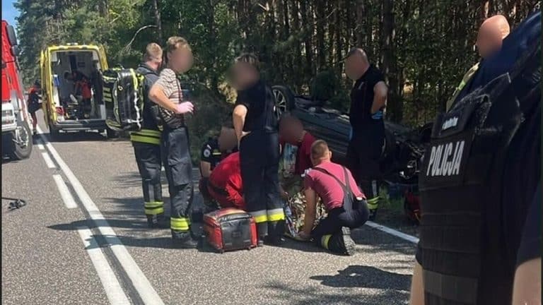 Na drodze krajowej nr 58 w pobliżu Dąbu leży rozbity samochód, wokół ratownicy i policjanci udzielają pomocy poszkodowanym.