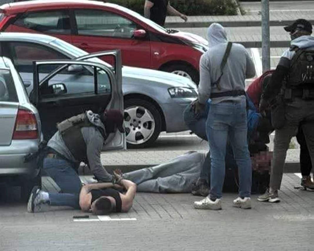 Policjanci zatrzymują mężczyznę na ulicy podczas akcji przeciw narkotykom w Olsztynie.