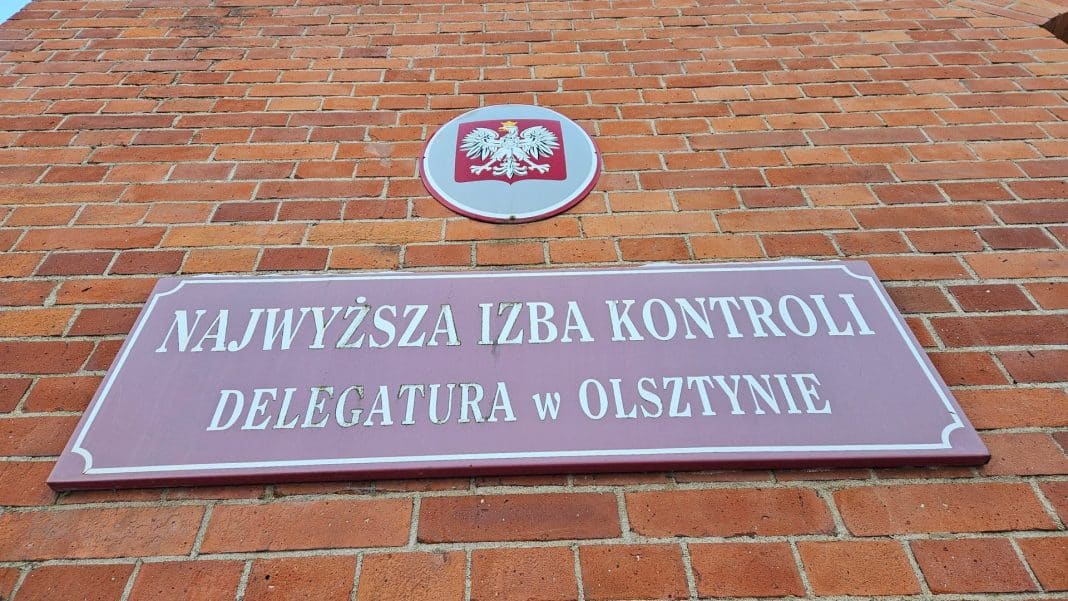 Tablica i herb Polski na ceglanej ścianie budynku urzędu w Olsztynie.