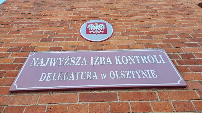 Tablica i herb Polski na ceglanej ścianie budynku urzędu w Olsztynie.