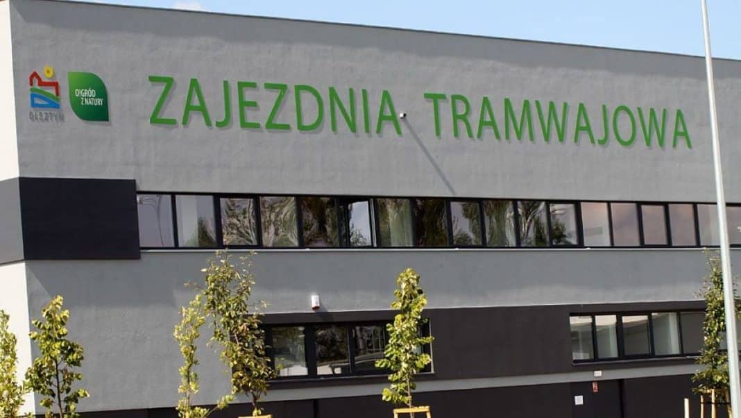 Budynek z napisem Zajezdnia Tramwajowa i logo Ogród z Natury na szarej ścianie.