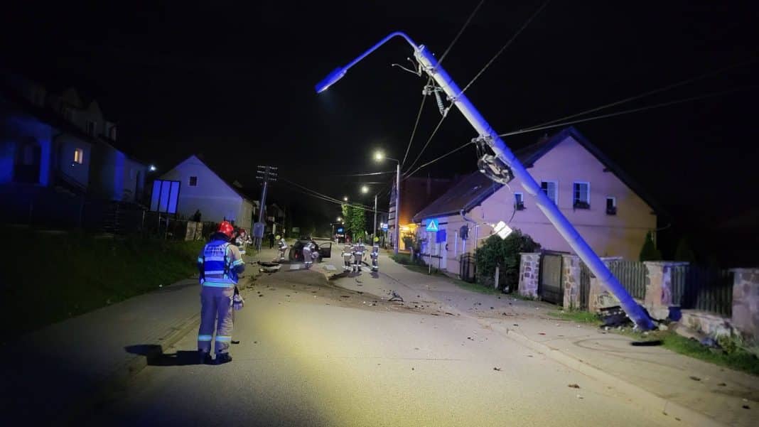 Wygięty słup energetyczny po uderzeniu samochodem w Rydzewie, nocna akcja służb ratunkowych.
