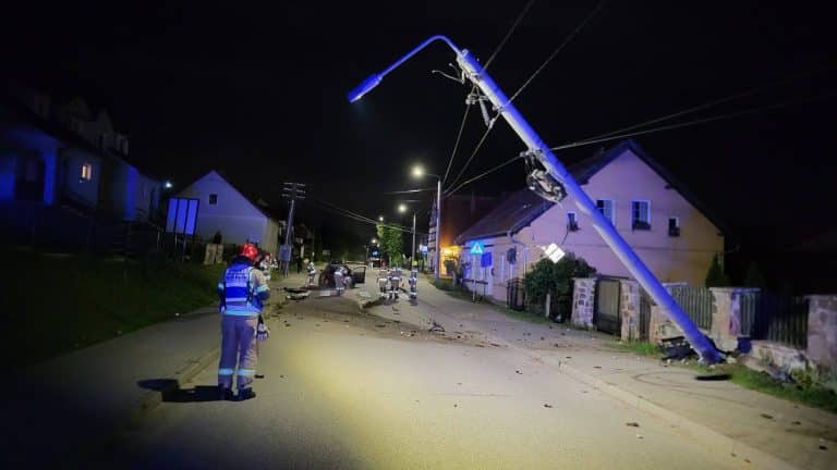 Wygięty słup energetyczny po uderzeniu samochodem w Rydzewie, nocna akcja służb ratunkowych.