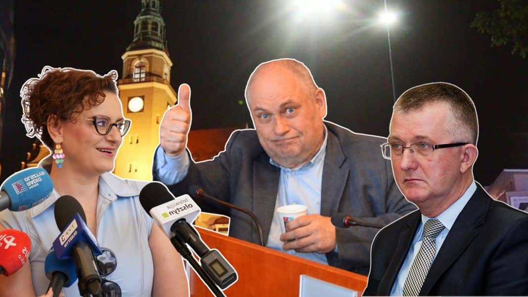 Zdjęcie przedstawia trzy osoby podczas konferencji, z mikrofonami i w tle wieża ratusza w nocy.