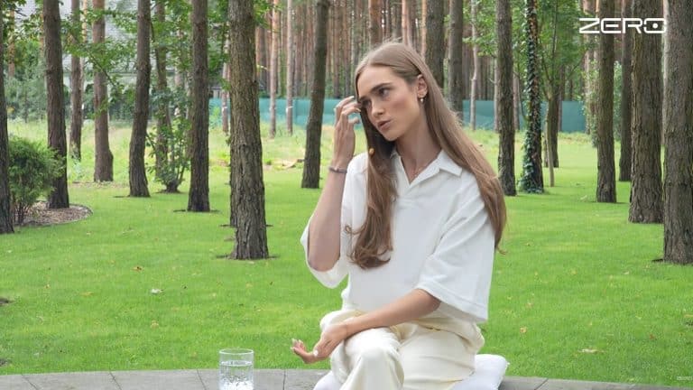 Zawodniczka Anastazja Kuś podczas rozmowy na ławce w parku, w tle drzewa i zieleń.
