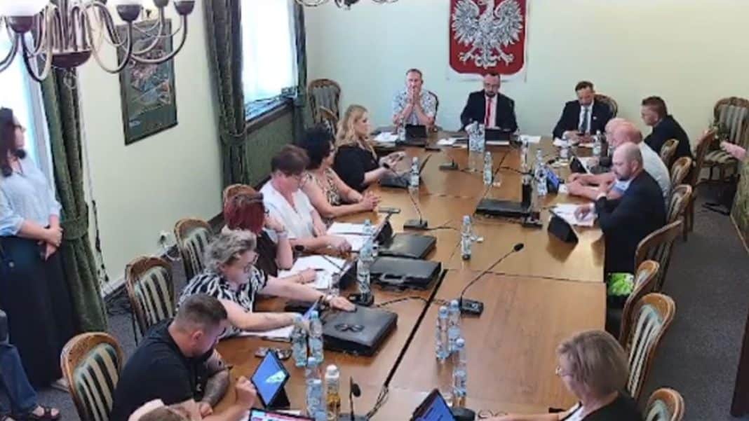 Gorąca sesja rady gminy Gietrzwałd z uczestnikami dyskusji przy stole i na stojąco.