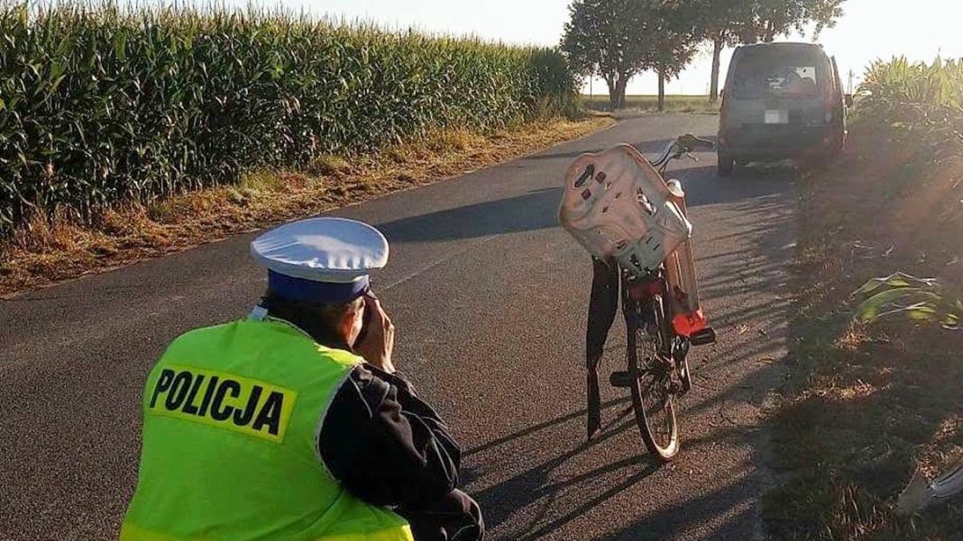 Policjant przy rowerze na drodze w Małych Bałówkach, w tle samochód.