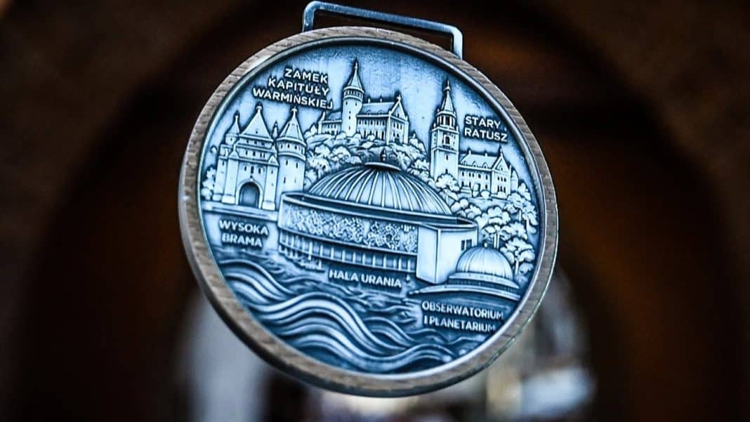Medal z widokiem na charakterystyczne budynki i zamki Olsztyna, z nazwami obiektów.