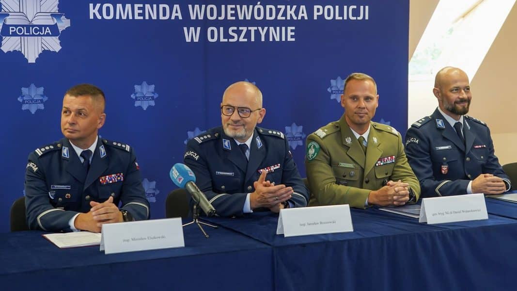 Uczestnicy konferencji w mundurach policyjnych i wojskowych podczas podpisania porozumienia w Olsztynie.