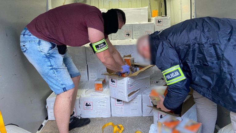 Funkcjonariusze przeszukują samochód, w którym ukryte są paczki z wyrobami akcyzowymi.