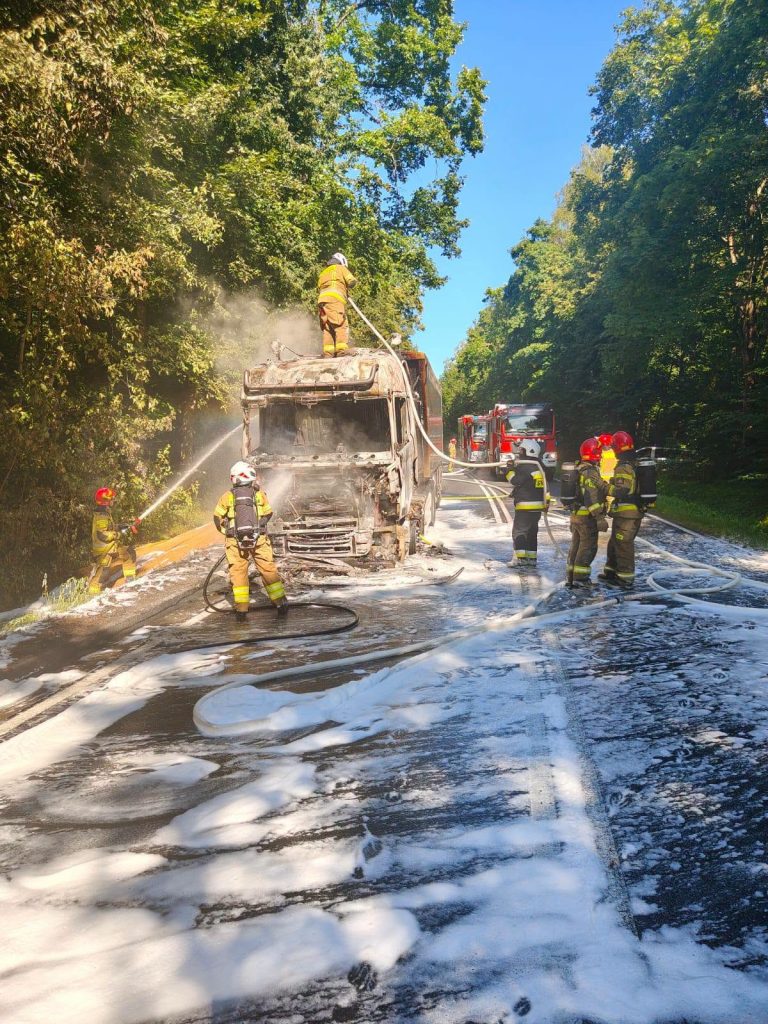 Strażacy gaszą pożar ciężarówki na drodze krajowej nr 16, wokół rozlana piana gaśnicza.
