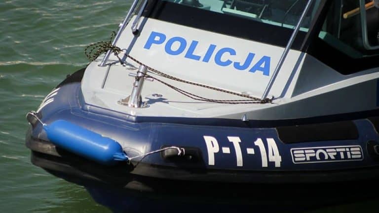 Policja na łodzi patrolowej przy plaży miejskiej, widoczny napis 'POLICJA' i numer jednostki.