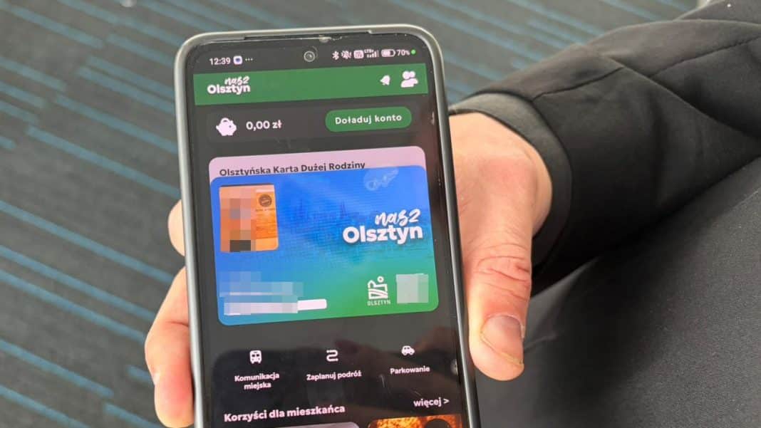 Smartfon z ekranem pokazującym aplikację miejską 'Nasz Olsztyn' z opcjami do zakupu biletów i sprawdzania autobusów.