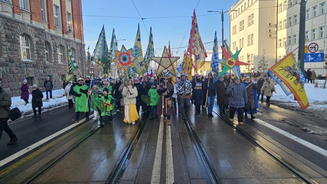 Uczestnicy marszu równości z flagami i symbolami na ulicy w zimowej scenerii.