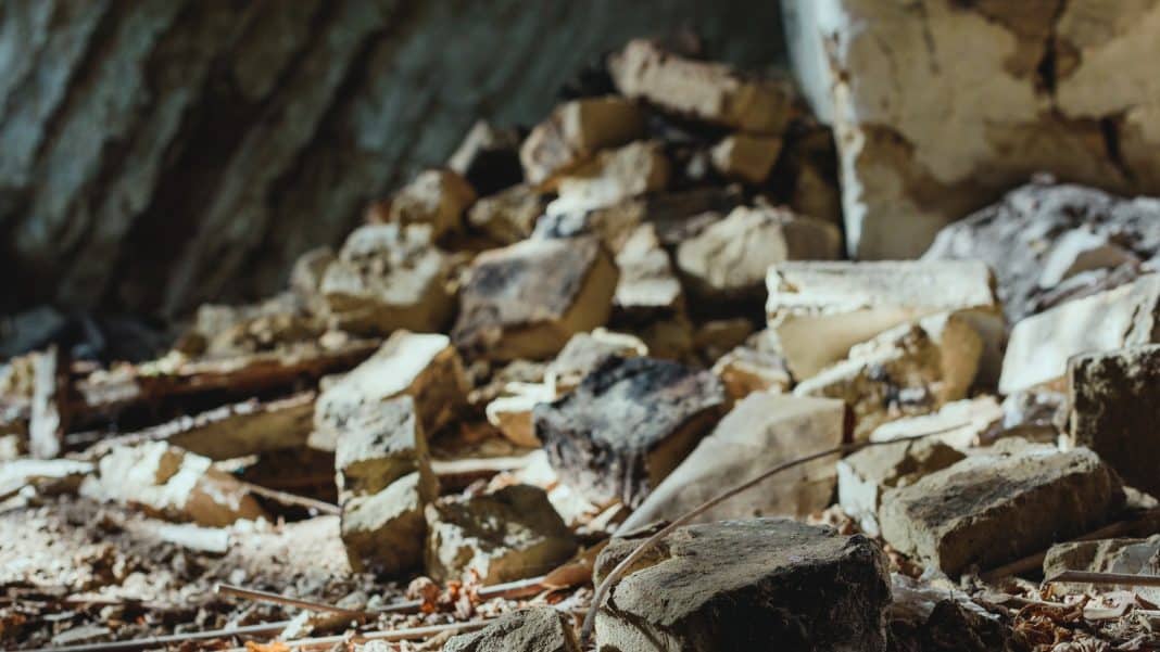 Fragmenty cegieł i elewacji na chodniku po zawaleniu się ściany budynku przy ul. Kajki w Jezioranach.