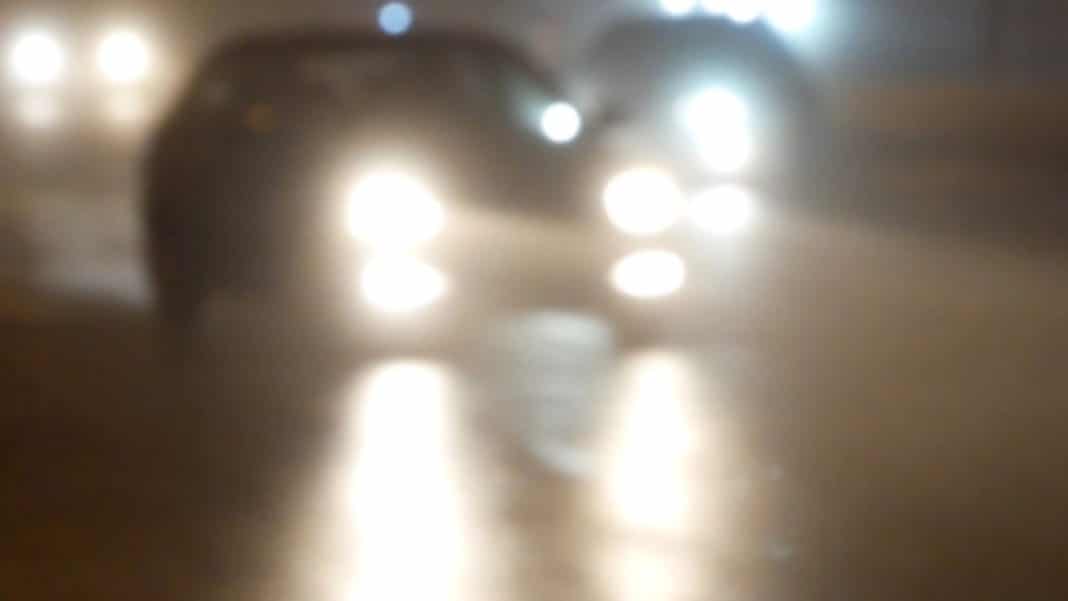 Zdjęcie przedstawia nieostre światła i sylwetkę osoby w ciemnym pomieszczeniu.
