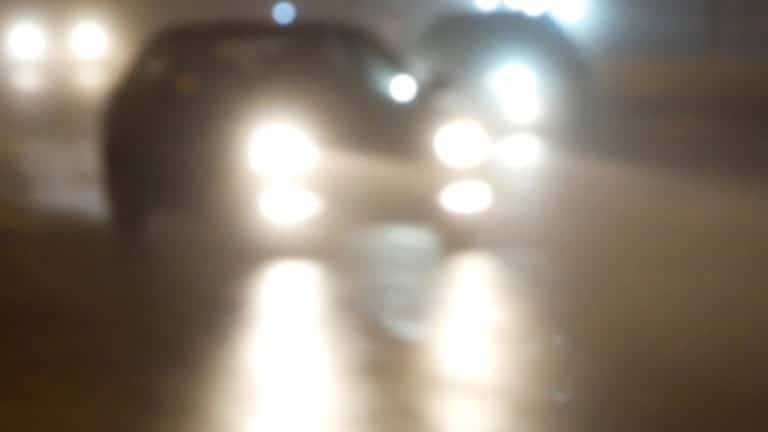 Zdjęcie przedstawia nieostre światła i sylwetkę osoby w ciemnym pomieszczeniu.