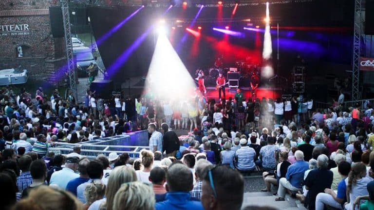 Publiczność na koncertowej scenie podczas festiwalu muzyki metalowej w centrum Olsztyna.