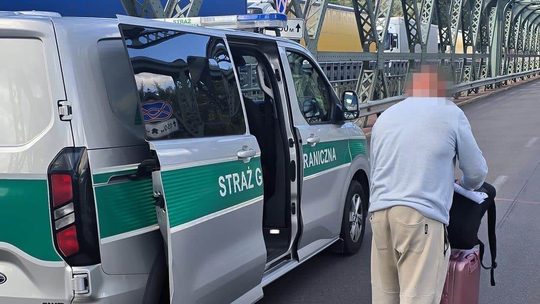 Mężczyzna z walizkami obok samochodu Straży Granicznej na moście w Olsztynie.