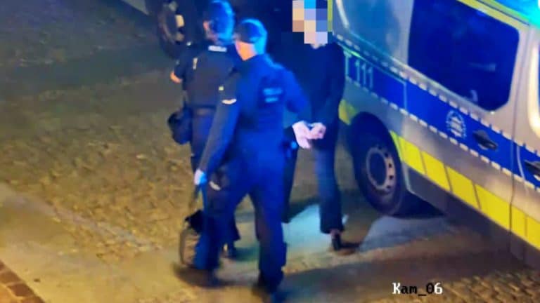 Kobieta i mężczyzna zatrzymani przez policję na Starym Mieście w nocy, obok radiowozu.
