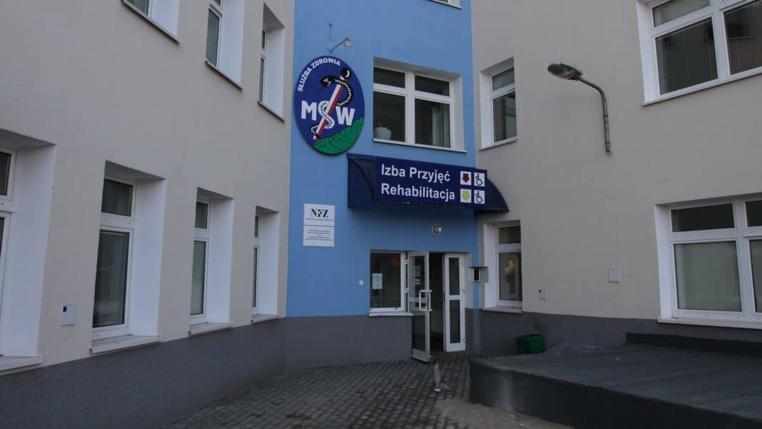 Budynek szpitala z oznaczeniem Izba Przyjęć i Rehabilitacja na zewnątrz.
