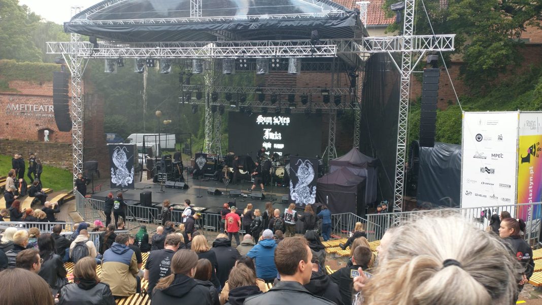 Widok na scenę festiwalową w amfiteatrze, z tłumem widzów i nagłośnieniem.