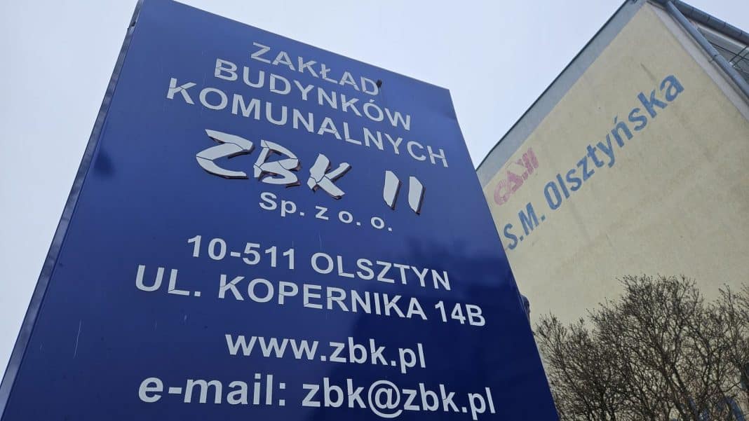 Tablica informacyjna Zakładu Budynków Komunalnych w Olsztynie, z widocznymi danymi kontaktowymi i adresem.