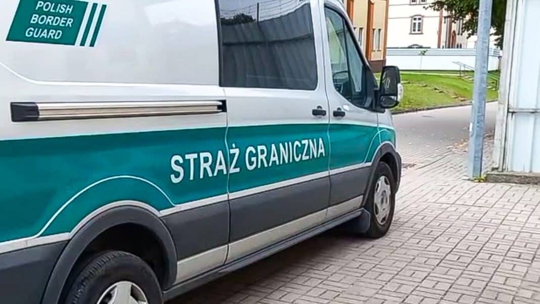Samochód Straży Granicznej na ulicy, widoczny napis 'STRAŻ GRANICZNA' na boku pojazdu.