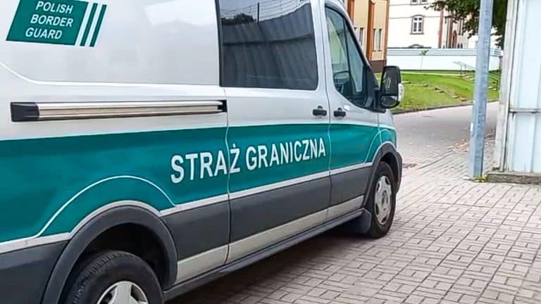 Samochód Straży Granicznej na ulicy, widoczny napis 'STRAŻ GRANICZNA' na boku pojazdu.