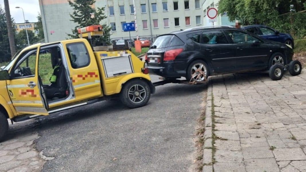Samochód odholowany przez służby miejskie z chodnika przed szkołą w Olsztynie.