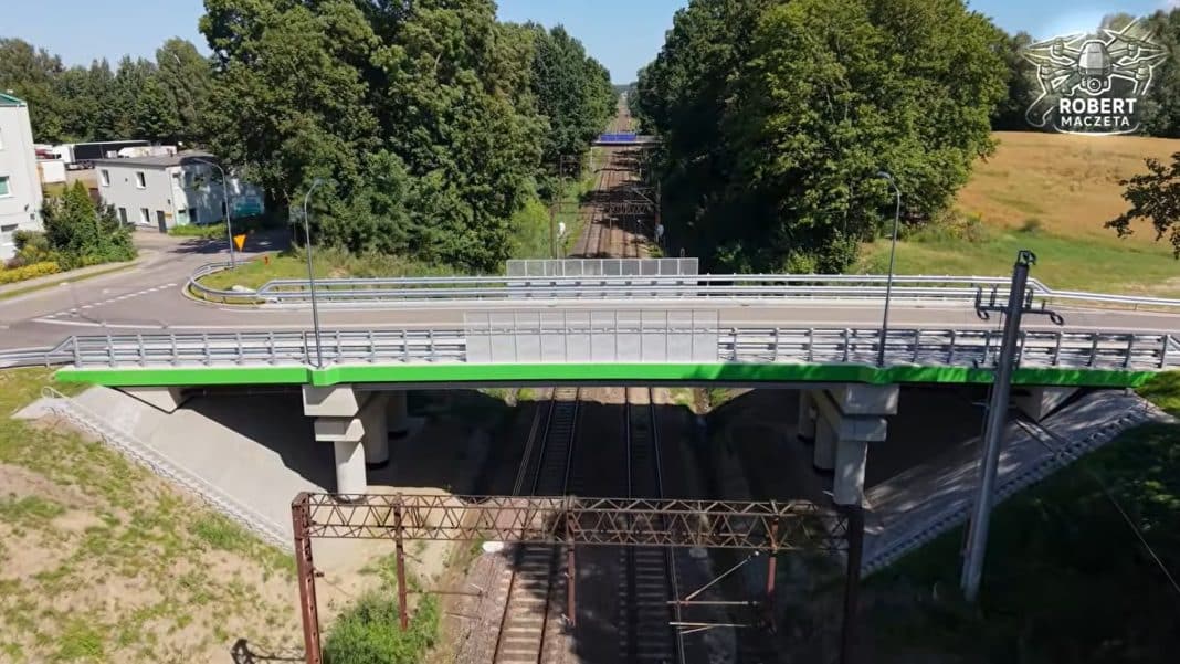 Nowy wiadukt nad torami w Olsztynie, widok z góry, otoczony zielenią i infrastrukturą kolejową.