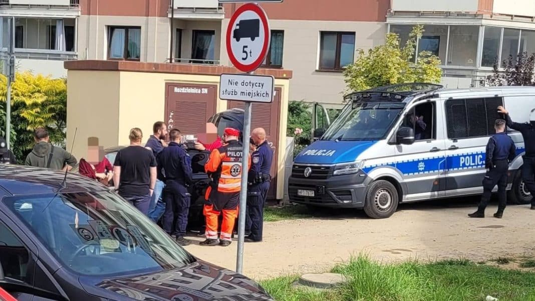 Grupa policjantów i ratowników na ulicy podczas akcji poszukiwawczej w Olsztynie, obok radiowozów i sprzętu ratunkowego.