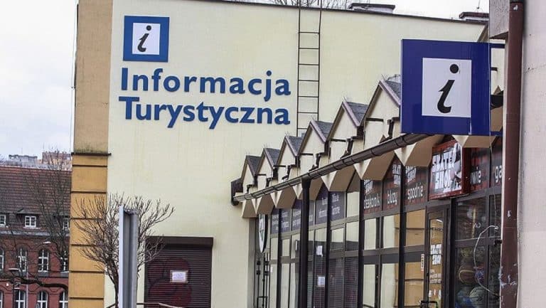 Budynek z dużym napisem 'Informacja Turystyczna' na ścianie, widok na wejście do punktu informacji.