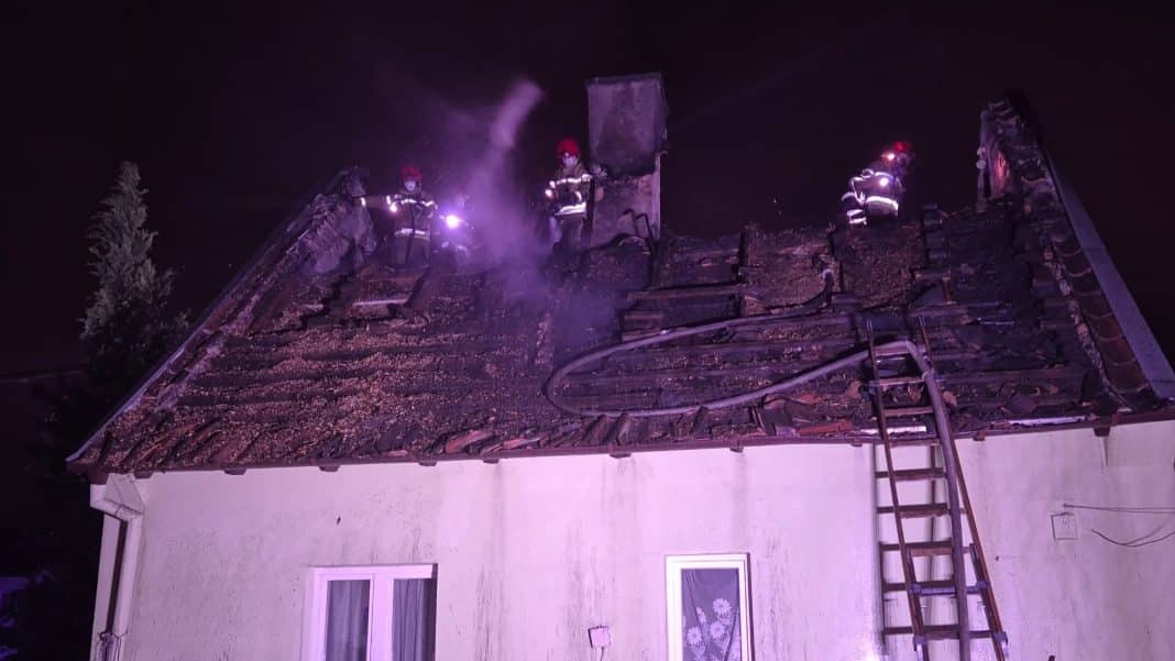 Strażacy gaszą pożar dachu domu jednorodzinnego w Olsztynie w nocy.