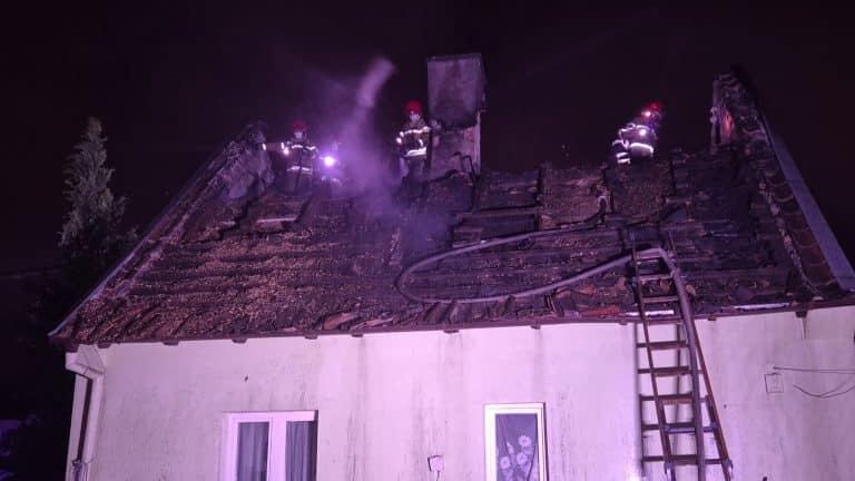 Strażacy gaszą pożar dachu domu jednorodzinnego w Olsztynie w nocy.