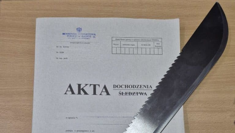 Dokument policyjny i maczeta na drewnianym stole, związane z sprawą przemocy domowej.
