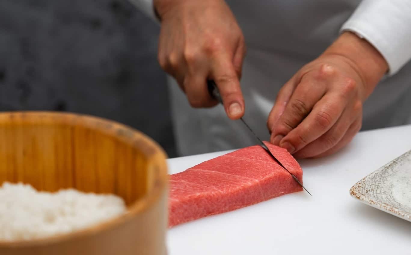 Kucharz kroi surowe mięso na desce w japońskiej restauracji Rin Omakase w Olsztynie.